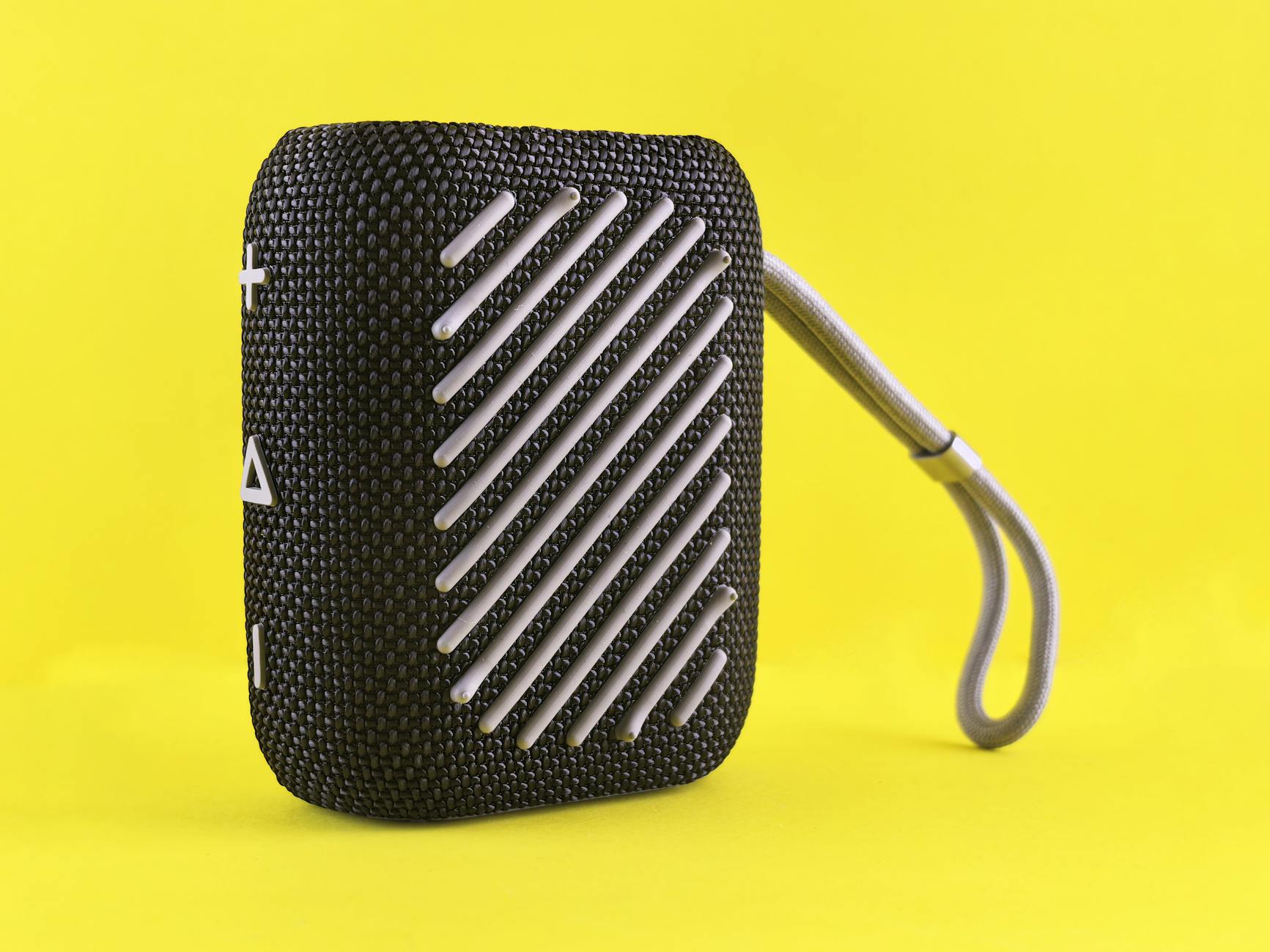 Black portable Bluetooth speaker with strap on a bright yellow backdrop, showcasing modern design.